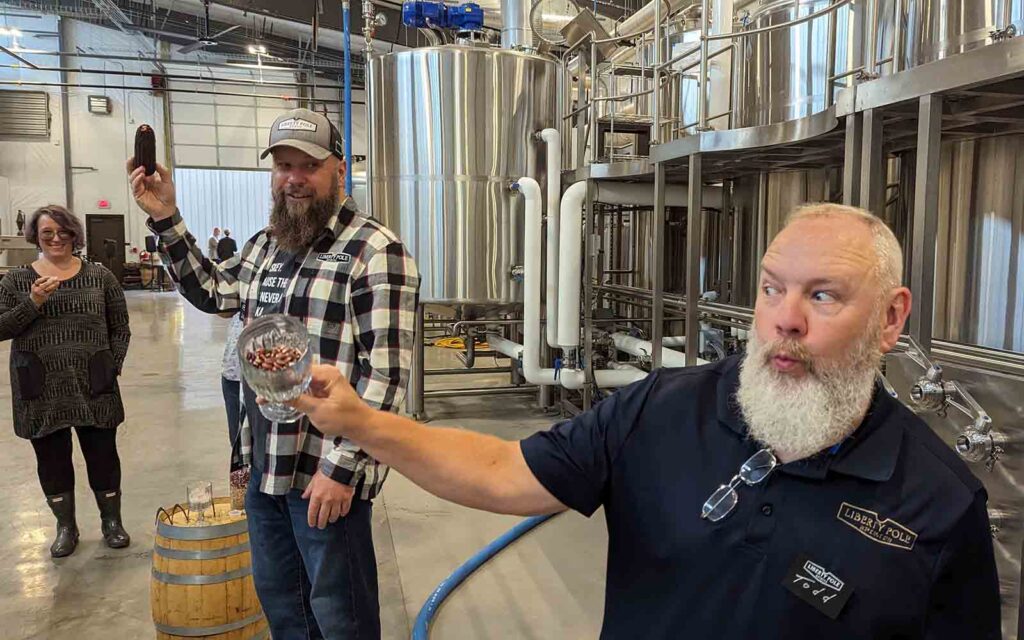 Two men lead a tour of a distillery.