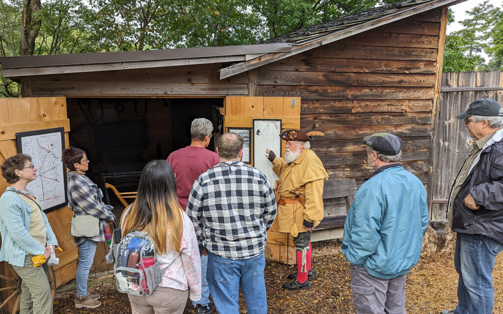 A small group gathers around an interpreter in period clothing.