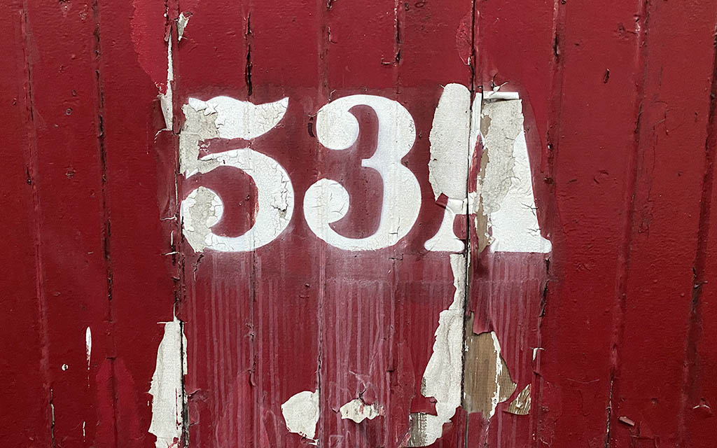 An image of the 53A on painted on wooden boards with peeling red paint. 