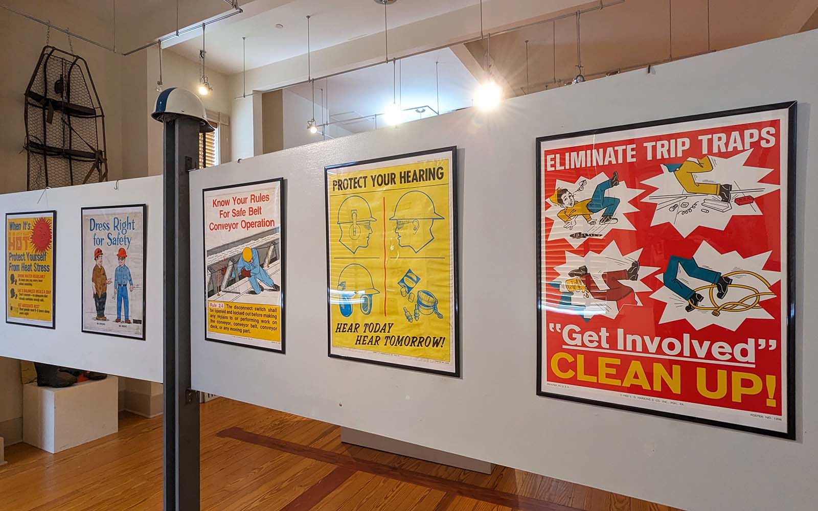 Vibrant, framed illustrated posters encouraging safety hang on a gallery wall.