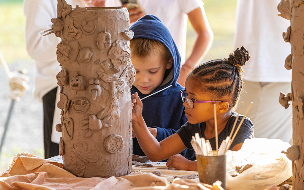 Young children work together on clay sculpture.