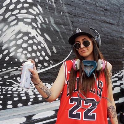 Artist Ally Grim poses in front of a mural