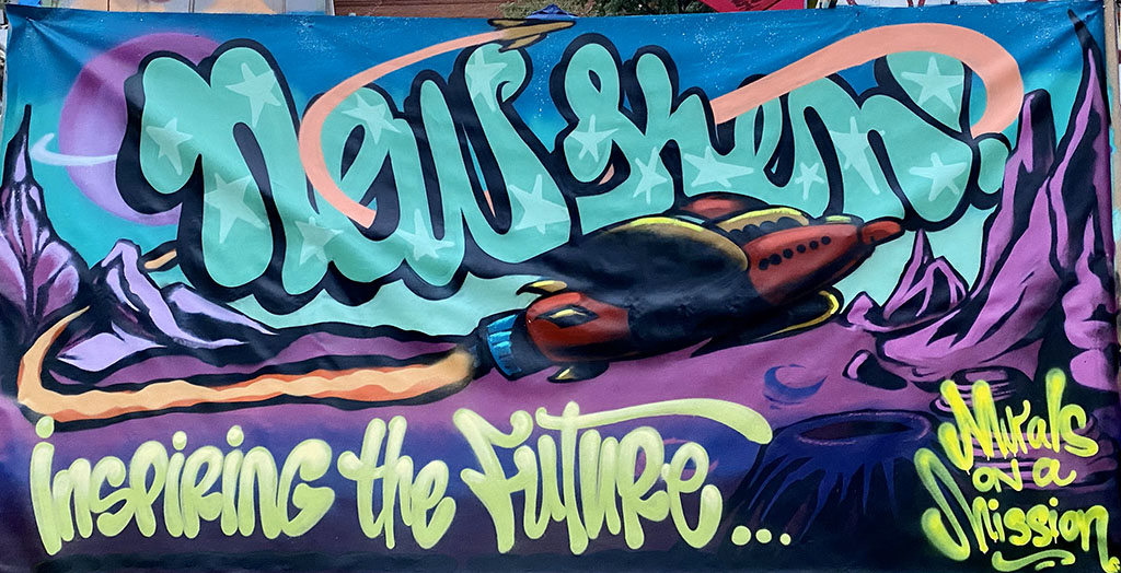 a graffiti art mural with a rocket reading "inspiring the future" and "murals on a mission"