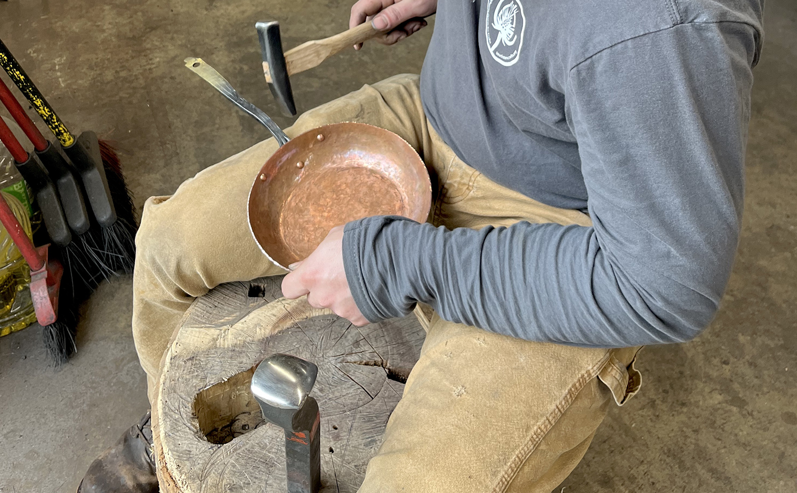 Participant working on copper smithing a frying pan using a hammer