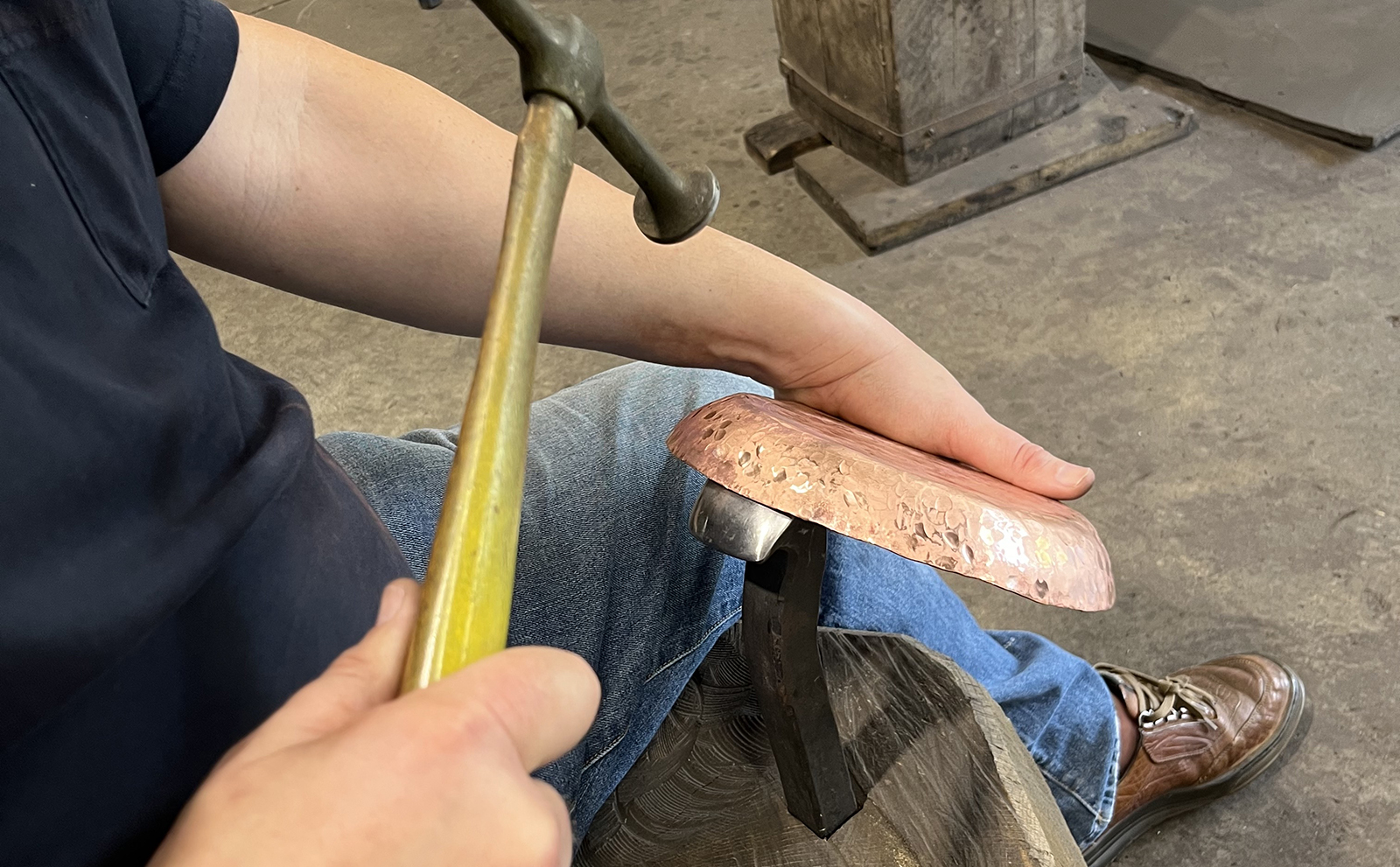 Participant working on copper smithing using a hammer