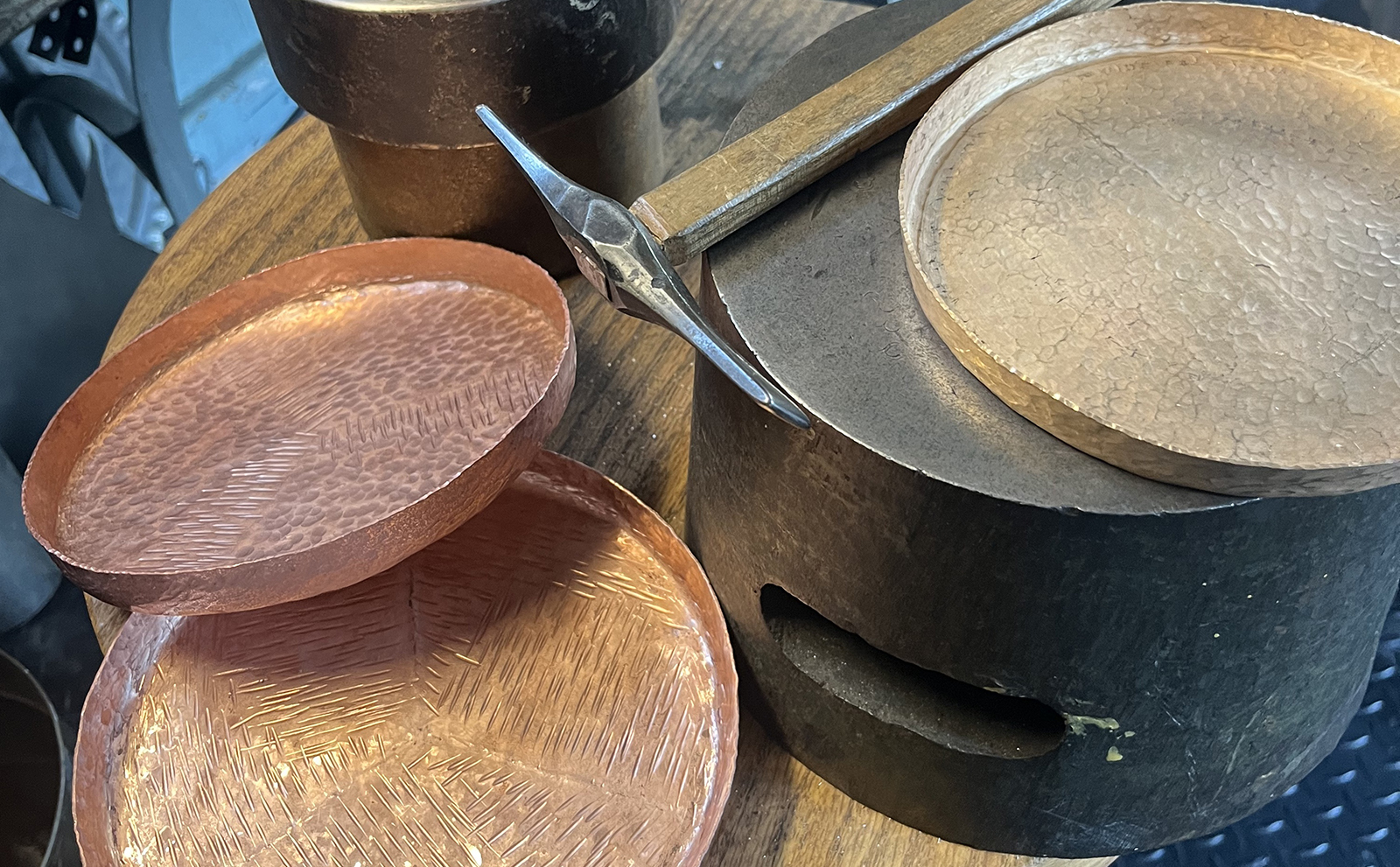 various copper trays shown alongside the hammer used for copper smithing