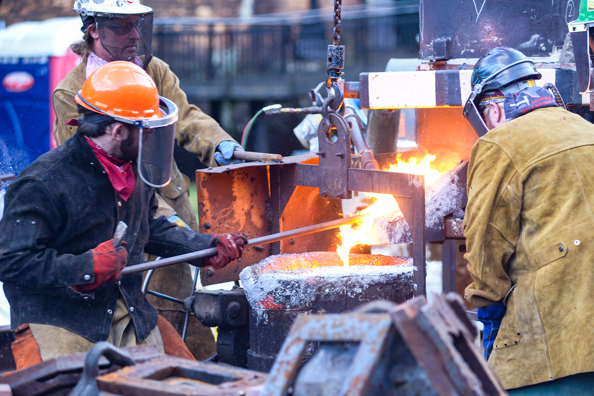 Three workers tending to the fire for an Iron Pour at the the Festival of Combustion.